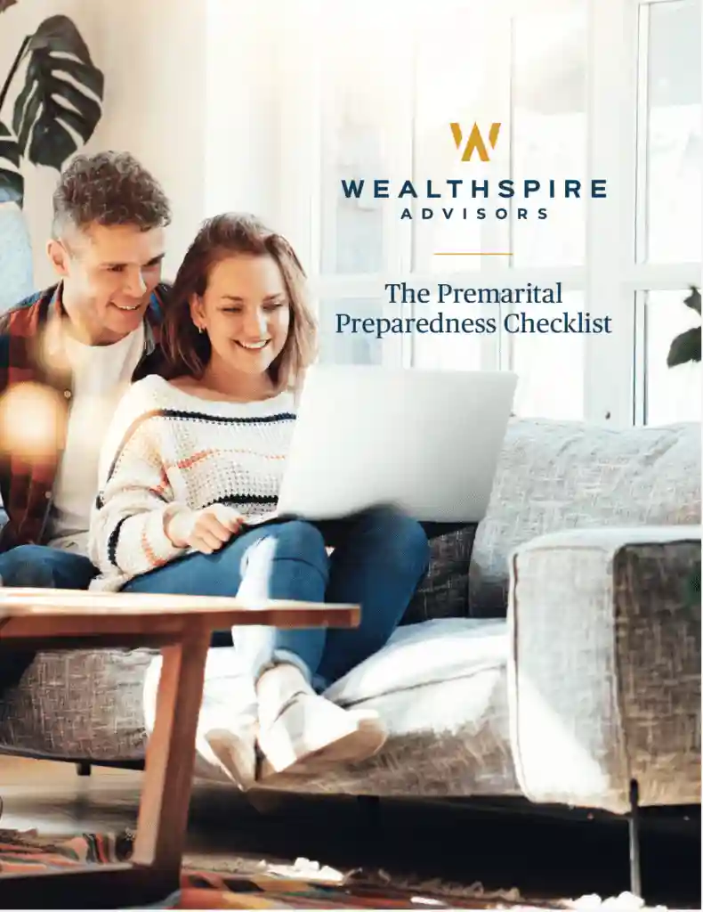 A happy couple lounging on a couch while interacting with a laptop computer.