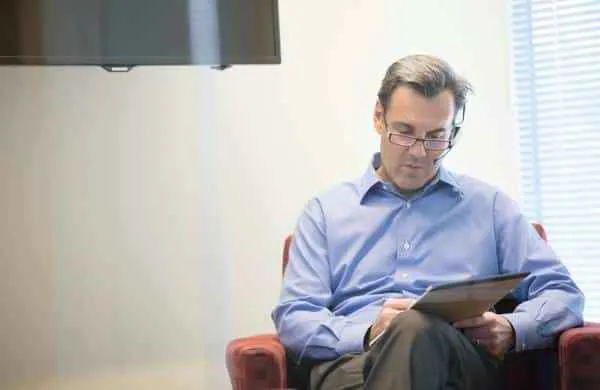 Man with a headset writing on a pad.